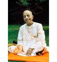 Prabhupada Smiling Sitting on Orange Blanket on Grass