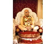 Srila Prabhupada on Cream Colored Vyasanasna with Many Flower Garlands